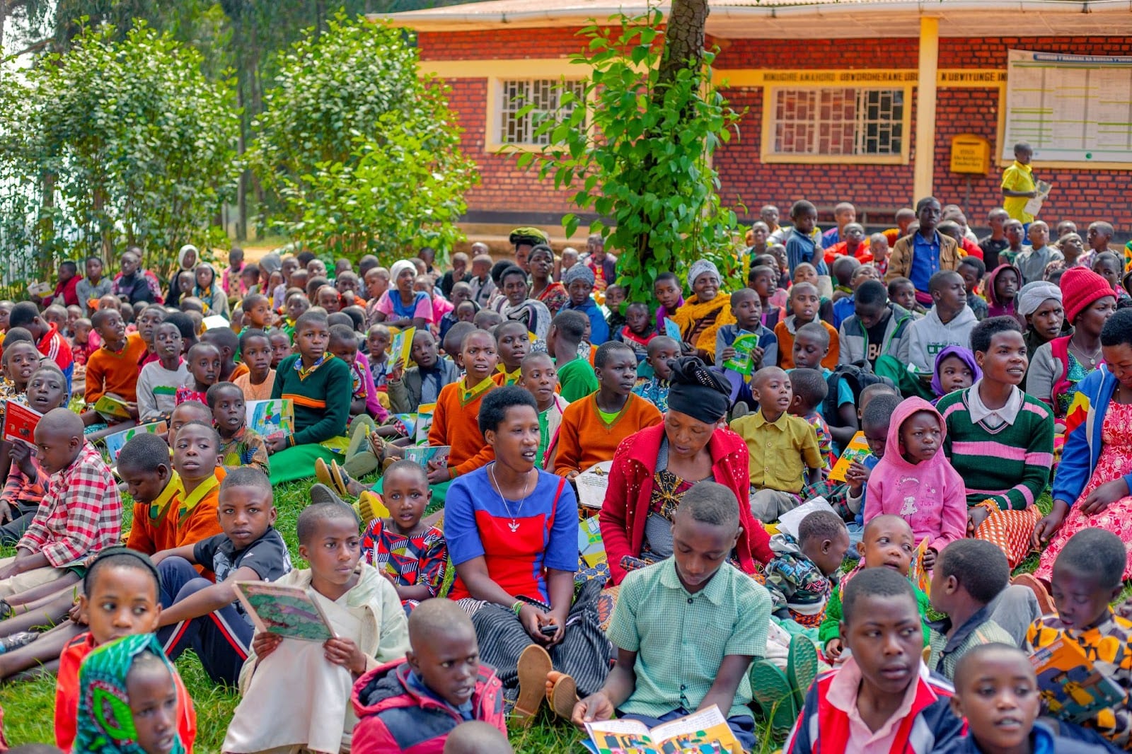 Children, caregivers, and parents reading books during the Umuganda Literacy program in Bungwe Community Library.